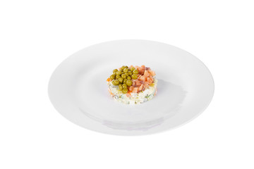 Russian salad with peas, red fish, chum salmon, eggs, cucumbers, carrots, potatoes on plate, side view white isolated background