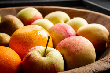 Fresh Apples and Orange in wooden bowl.