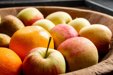 Fresh Apples and Orange in wooden bowl.