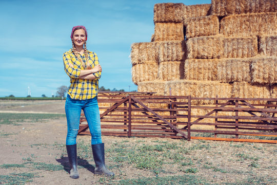 Farmer woman on her farm standing in front of straw