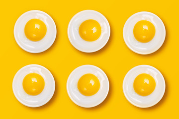 Raw Eggs on White Plates on Yellow Background