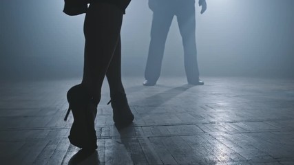 Legs of tango dancers in dark smoky studio. Woman goes to man. Woman legs on heels. Close-up shot in 4K, UHD