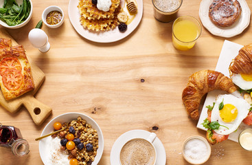 Overhead shot of brunch menu on wooden table with copy space.  Healthy sunday breakfast with croissants, waffles, granola and sandwiches. Flatlay with tasty food