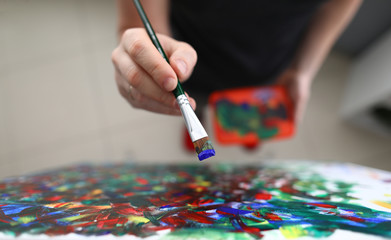 To view of persons hand applying oil paint on picture. Colourful brush strokes on canvas. Creative...