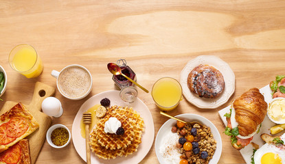 Brunch flatlay on wooden table. Healthy sunday breakfast with croissants, waffles, granola and...