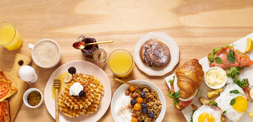 Brunch flatlay on wooden table. Healthy sunday breakfast with croissants, waffles, granola and...
