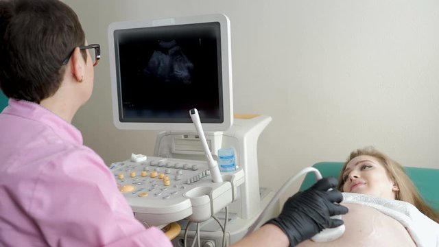 Process of ultrasonography, doctor checking baby in happy pregnant woman belly, modern medical technology