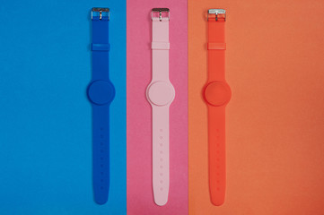 Three silicone clean wristwatches for fitness and sports. Blue, pink and orange silicone hand accessories. Tricolour.