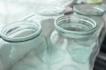 Many empty glass jars without lids of different sizes near the window. Lifestyle photos.