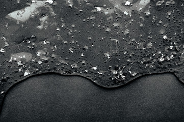 Transparent slime with spangles and oxygen bubbles flows down on a clear black background with...