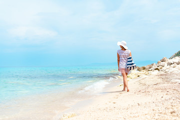 Fototapeta na wymiar A women in white with sunglasses enjoying on the beach