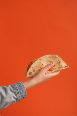 Mexican national food taco or Tatar national food kystyby in hand on an orange background.Food in a tortilla.National food concept