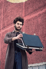 Curly man with a beard opened his suitcase.