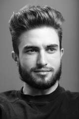 Fototapeta premium Close-up black and white portrait of a young handsome Caucasian male in studio. A man shows different human emotions.