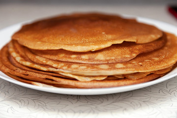 A stack of delicious hot and fresh thin pancakes baked in a pan of milk, flour and eggs for breakfast at home. Russian national holiday Shrovetide.