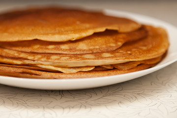 A stack of delicious hot and fresh thin pancakes baked in a pan of milk, flour and eggs for breakfast at home. Russian national holiday Shrovetide.