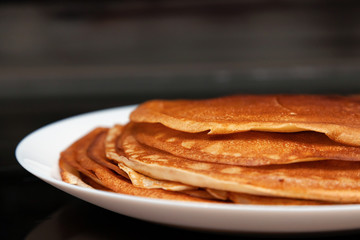 A stack of delicious hot and fresh thin pancakes baked in a pan of milk, flour and eggs for breakfast at home. Russian national holiday Shrovetide.