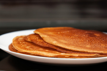 A stack of delicious hot and fresh thin pancakes baked in a pan of milk, flour and eggs for breakfast at home. Russian national holiday Shrovetide.