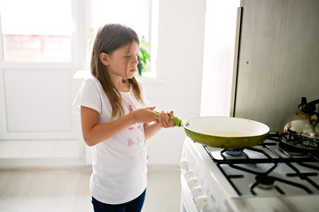 child fries in a pan scrambled eggs with bacon