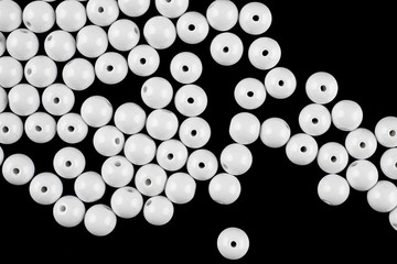 A scattering of white beads on a black background