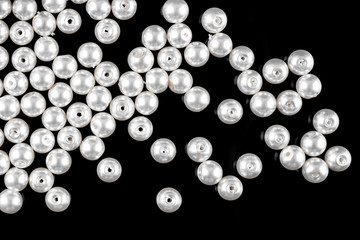 A scattering of white pearl beads on a black background
