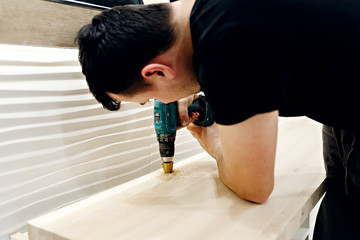 man drills a washbasin hole in the bathroom,home repair work in the bathroom,puncher at work,drill