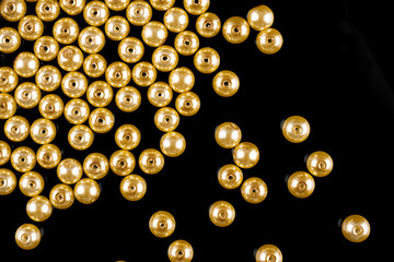 A scattering of yellow pearl beads on a black background