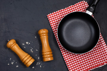 Empty black frying pan or skillet with pepper and sea salt