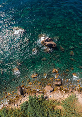 Top down aerial view of rocky beach, coastline of the village of Nerano. Wild beach of Italy. Turquoise, blue surface of the water. Vacation and travel concept. Beautiful sunny day. Vertical photo
