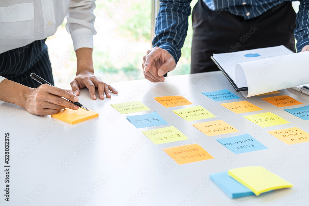 Poster Two creative business people meeting and planning use post it notes sticky note on desk to share idea, Analysis data chart and graph with teamwork strategy brainstorming in office
