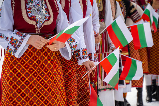Bulgarian Flag. Woman holding Flag of Bulgaria in traditional clothing. Day of Liberation parade. National holiday with people celebrating. Patriotic scene people waving flags.