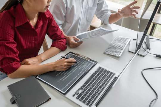 Two professional programmer cooperating and working on web site project in a software developing on desktop computer at company, codes and typing data code, Programming with HTML, PHP and javascript