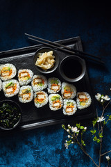 vegan sushi with tofu in General Tso sauce, avocado and fresh vegetables . on a table with branches of a blossoming tree