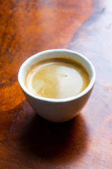 Cup of coffee in a nice hipster cafe. Soft focused image. Cup of espresso on old wooden table of cafeteria. 