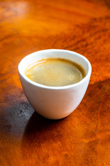 Cup of coffee in a nice hipster cafe. Soft focused image. Cup of espresso on old wooden table of cafeteria. 