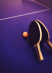 Table tennis rackets and ping pong ball on blue background