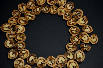 round frame made of halves of inshell walnut close-up on a black background horizontal orientation