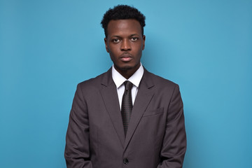 Handsome young African American serious businessman wearing a black suit and tie