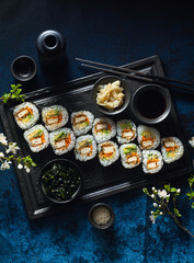 vegan sushi with tofu in General Tso sauce, avocado and fresh vegetables . on a table with branches of a blossoming tree