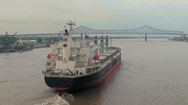 Aerial: Cargo ship on the Mississippi River and the city skyline at sunrise New Orleans, Louisiana, USA. 