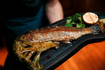 Baked fish lies in a plate.
