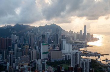 Cityscape Hong Kong districts at blue harbor against hills