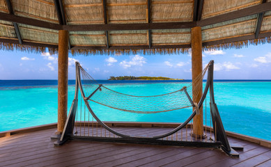 empty hammock in an overwater terrace on turquoise lagoon