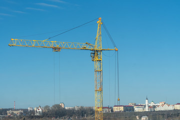 Fototapeta na wymiar yellow crane, crane on the background of the city and blue sky with clouds close-up, copy space