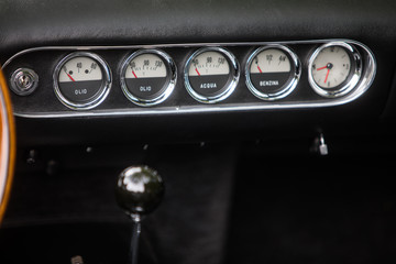 Clock, fuel level and thermometer on a vintage car's dashboard