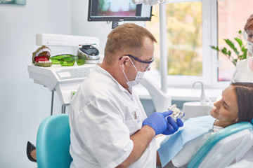 Obraz premium Doctor dentist treats teeth of a beautiful young girl patient. The girl on reception at the dentist. Doctor dentist treats tooth