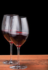 isolated two glasses with deep red wine on wood