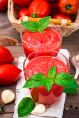 Blended fresh tomato juice with basil leaves in glasses  on a wooden table