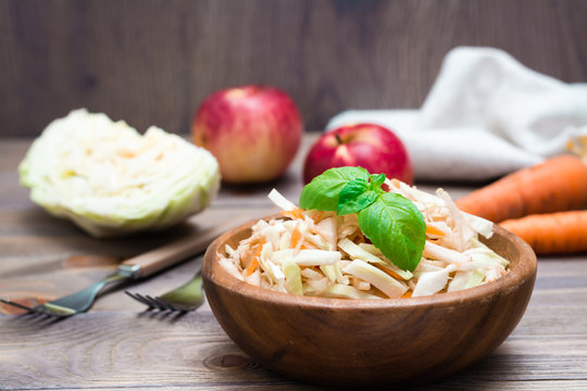 American Ready-to-eat Cole Slaw Salad Made From Cabbage, Celery, Carrots And Apples With Basil Leaves In A Wooden Plate And Ingredients For Cooking On A Wooden Table. Healthy And Eating Concept