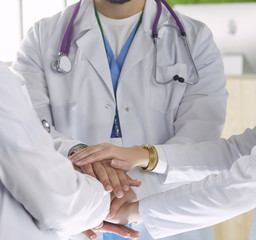 Team of medical workers holding hands together indoors, above view. Unity concept